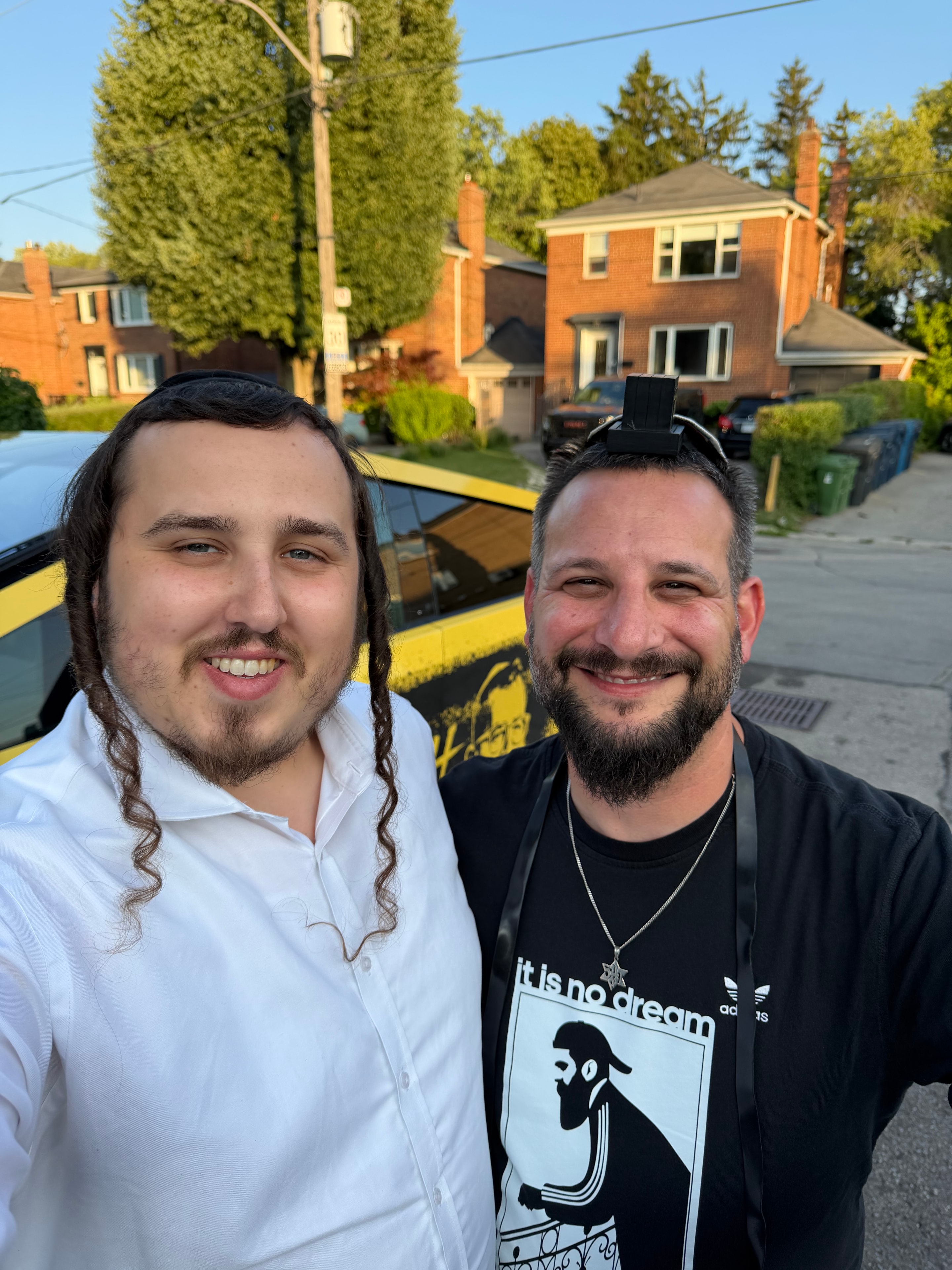 Two people smiling outdoors near the Mitzvah Truck