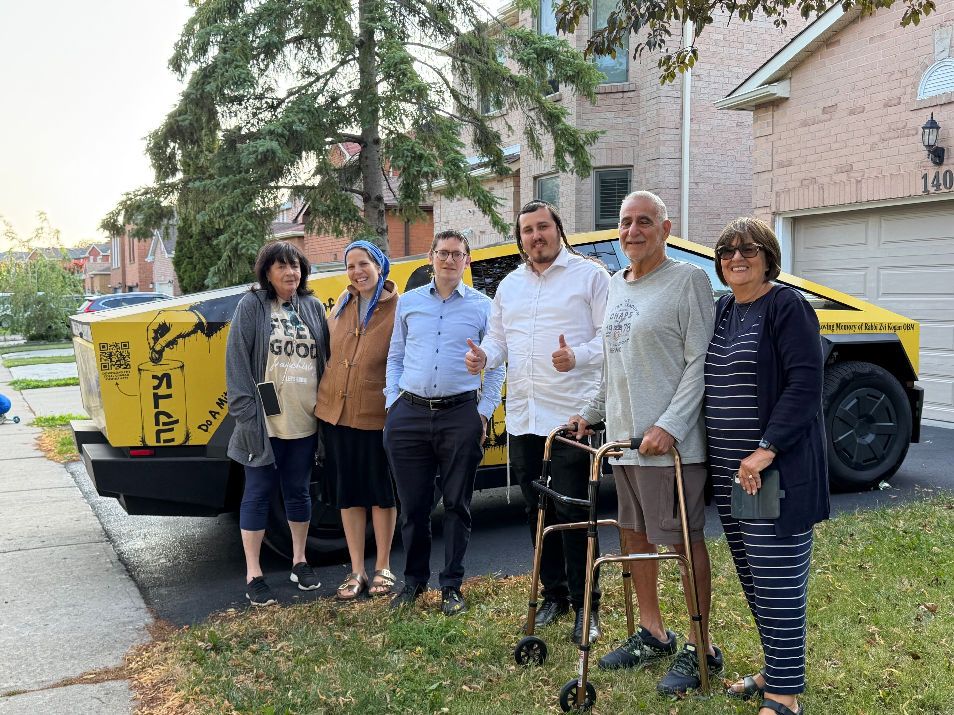 Group of six people posing with the Mitzvah Truck in a neighborhood