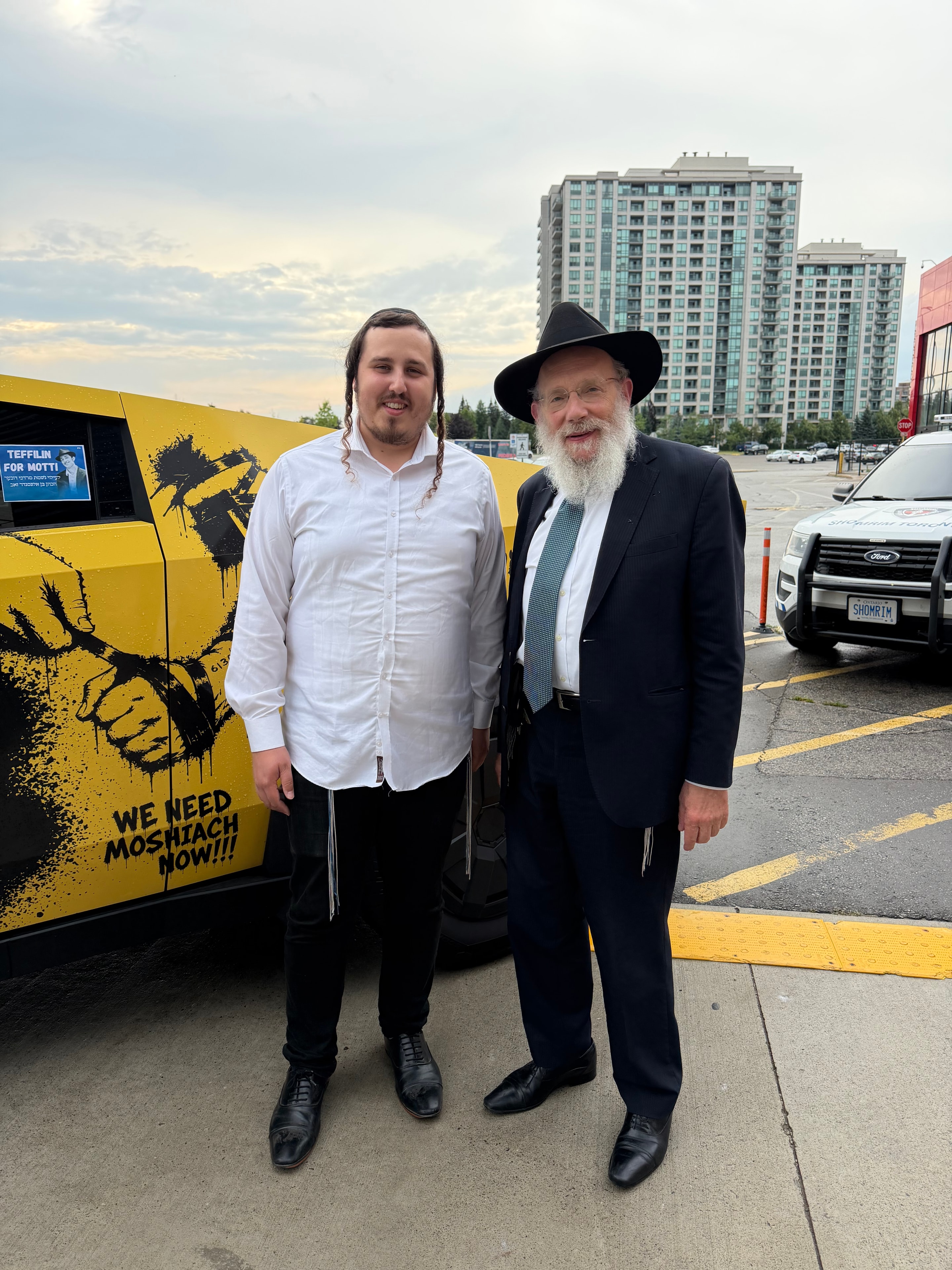Two people standing in front of the Mitzvah Truck